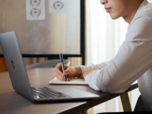 Asian male profile writing notebook laptop window