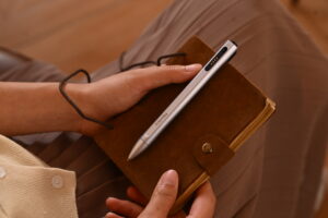 Female holding leather journal silver pen clipped lap